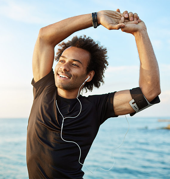 Man smiling, stretching on beach undergoing lifestyle changes and weight loss support.